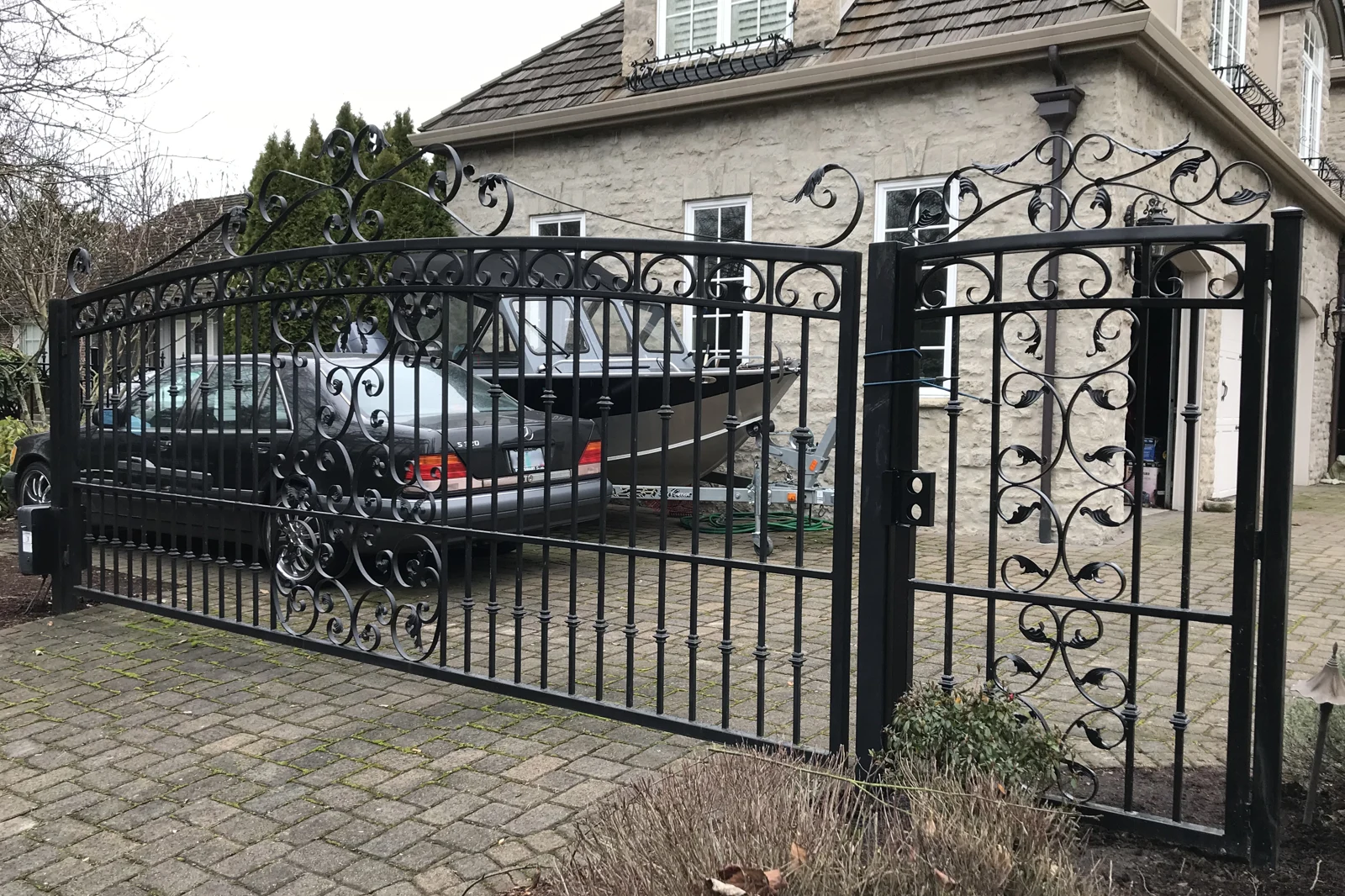 Ornate black wrought iron driveway and pedestrian gates with scrollwork