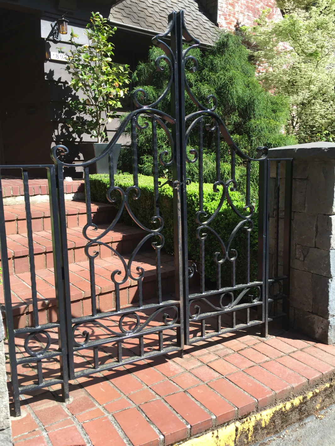 Ornate black wrought iron pedestrian gate with scrollwork
