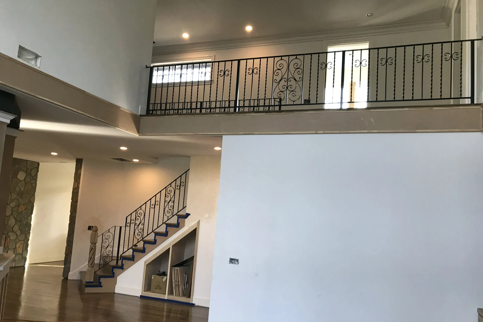 A custom-handcrafted residential interior railing system featuring black wrought iron with decorative scrollwork panels and twisted pickets.