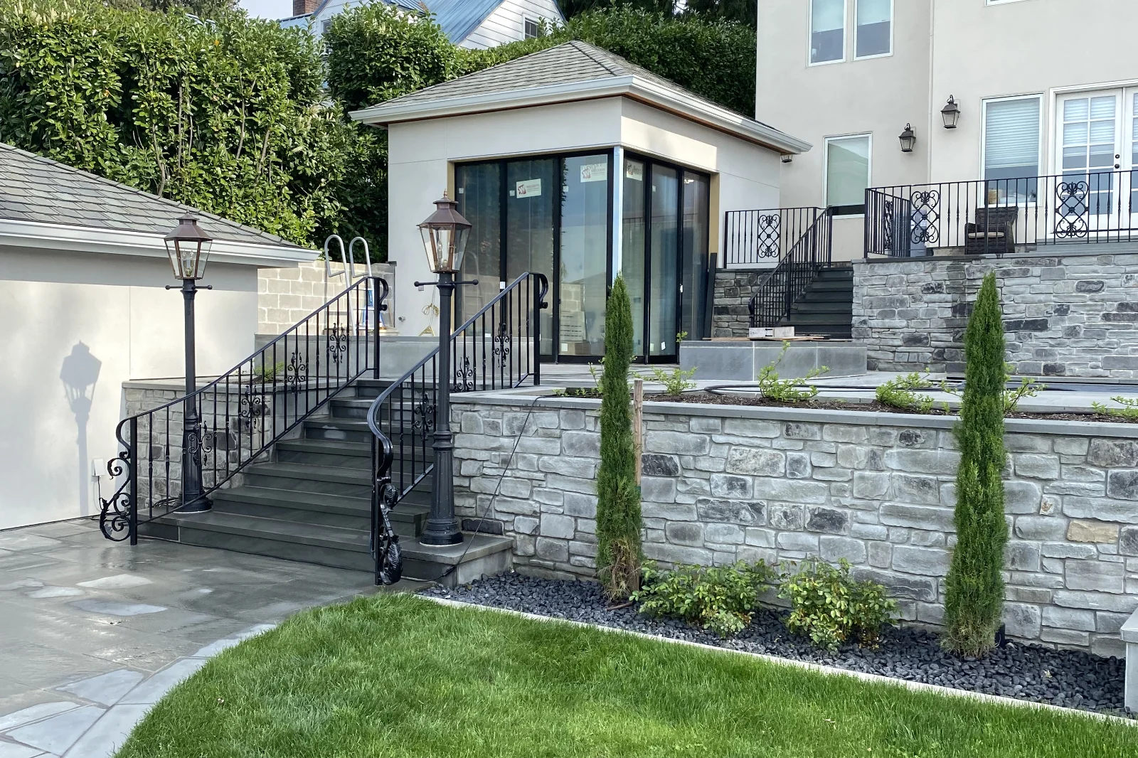 Custom wrought iron staircase railing with decorative scrolls and ornamental details, installed on stone outdoor stairs. | Chip and Dale's Iron Works