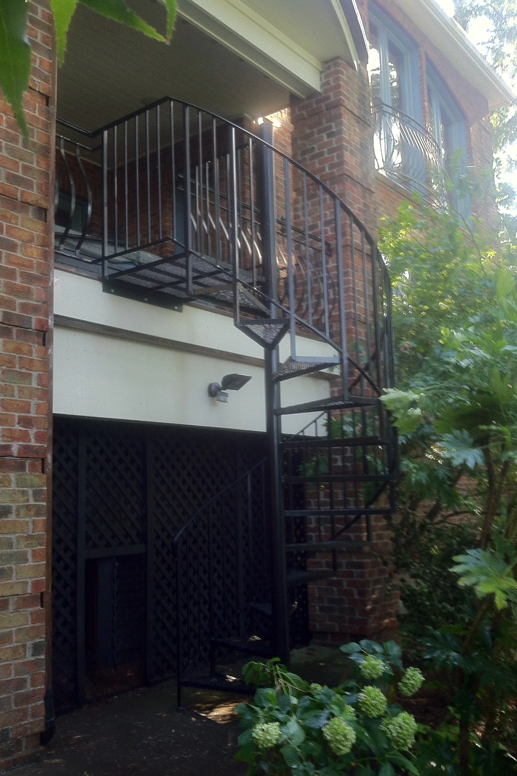 Black metal spiral staircase, featuring custom  diamond-tread steps and vertical balusters. | Chip and Dales' Iron Works